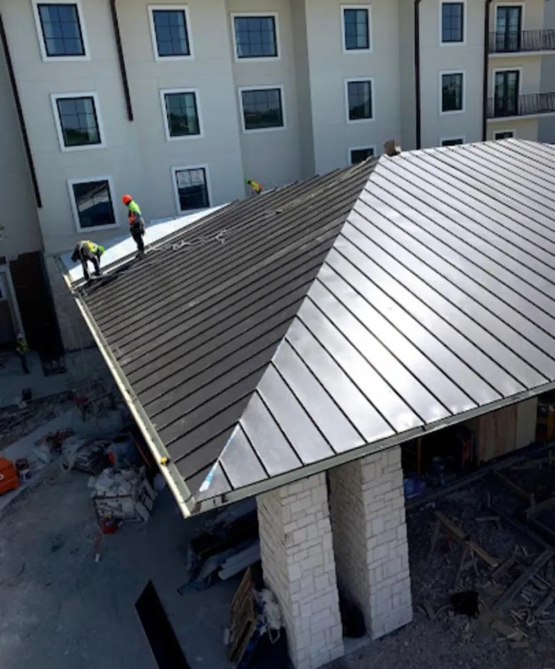 Crew installing standing seam metal roof panels on a commercial project in Huron